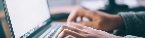 Mann tippt auf Computertastatur, was den Versand/ Empfang/ Bearbeitung einer E-Rechnung simulieren soll 