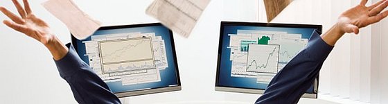 Zur Visualisierung von ZUGFerD zeigt das Bild einen Mann, der vor zwei Monitoren sitzt, auf denen verschiedene Grafiken zu sehen sind. Er wirft zahlreiche Unterlagen in die Luft.
