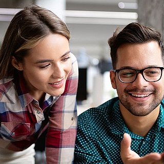 Ein Mann und eine Frau schauen gemeinsam auf einen Bildschrim