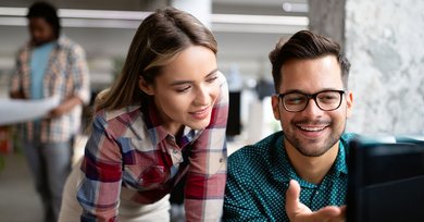 Ein Mann und eine Frau schauen gemeinsam auf einen Bildschrim