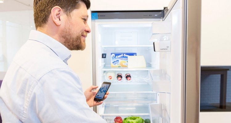 Fotografie Shopper Experience - Ein Mann steht mit seinem Smartphone vor einem Smart Home Kühlschrank Smart Home Kühlschränke mit Kameras zu erkennen, was wir nachkaufen müssen