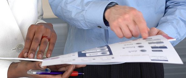 Eine Person zeigt einer anderen Person etwas auf Papier