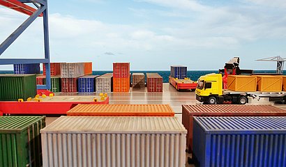 Containerhafen am helllichten Tag mit beladenem Lkw im Fokus 