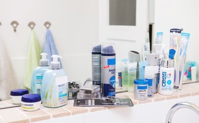 Kostmetikprodukte auf Ablage vor Badezimmerspiegel
