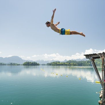 Foto zeigt einen Mann in der Luft, ins Wasser springend 