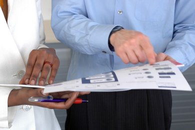 Zwei Personen halten eine Informationsmappe und zeigen auf die Inhalte.