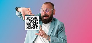 Symbolbild für 2D.Code mit GS1 Digital Link: Ein junger Mann hält mit einem GS1 QR-Code