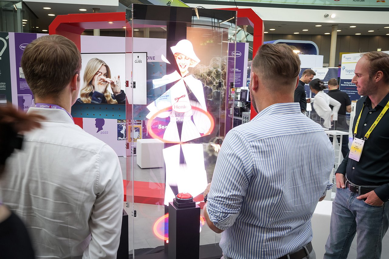 Personen auf einem GS1 Event schauen sich eine Hologrammprojektion von Henkel an