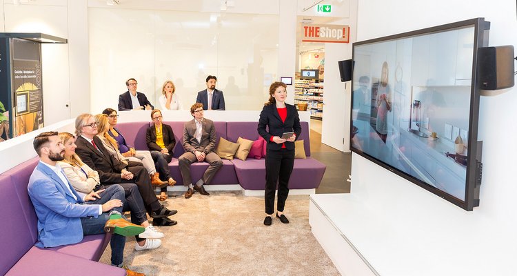 Fotografie Shopper Experience - Eine Gruppe von Personen sitzt vor einem Monitor in der Shopper Experience