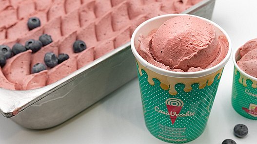Eiscreme in einem großen Behälter und in einem Becher