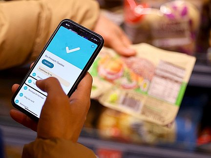 Person scannt mit der SoVi App auf dem Handy im Supermarkt ein Lebensmittelprodukt.