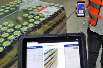 Foto eines Smartphones mit digitalem Lieferschein und einer Warenanlieferung