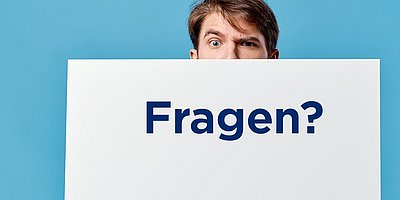 Ein junger Mann schaut über den Rand eines weißen Kartons