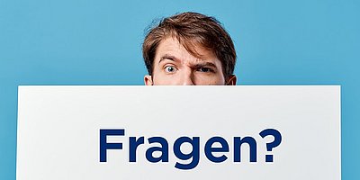 Ein junger Mann schaut über den Rand eines weißen Kartons