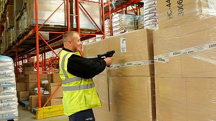 Efficient Unit Loads im Einsatz. Ein Mann scant mit einem Handscanner große Pakete.