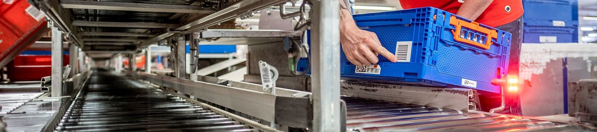 GS1 Smart-Box im Lager auf Fließband als Beispiel für eine wiederverwendbare Transportverpackung, gelabelt mit einem GRAI