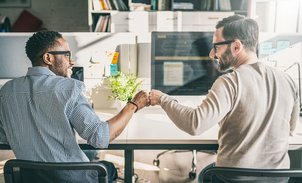 Zwei Männer geben sich im Büro einen Handschlag