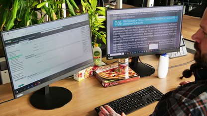 Mann am Schreibtisch vor zwei Bildschirmen beim Produktabgleich von Inhaltsangaben