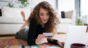 Online verkaufen Frau vor Laptop beim Onlineshopping mit Kreditkarte in der Hand