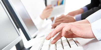 Person tippt auf einem Laptop