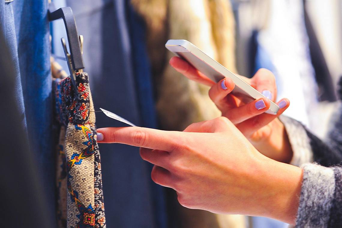 Eine Frau scannt das Etikett von einem Kleindungsstück