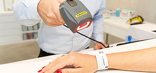 Fotografie Healthcare Experience - Im Krankenhaus wird das Band am Arm einer Patientin gescannt