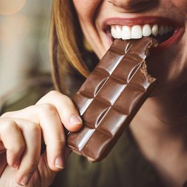 Eine Frau beißt in eine Tafel Schokolade