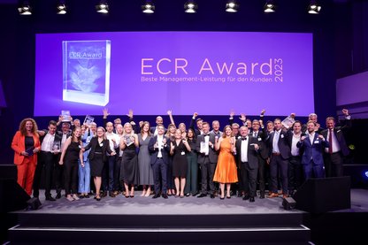 Gruppenbild der jubelnden Gewinnerteams vom ECR Award 2023 auf großer Bühne mit Trophäen