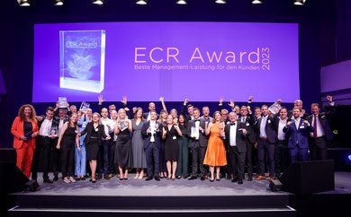 Gruppenbild der jubelnden Gewinnerteams vom ECR Award 2023 auf großer Bühne mit Trophäen