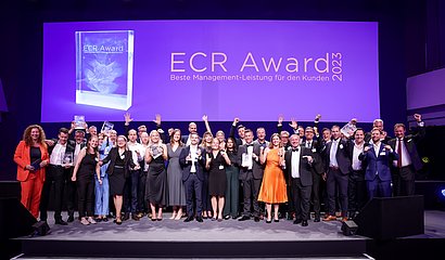 Gruppenbild der jubelnden Gewinnerteams vom ECR Award 2023 auf großer Bühne mit Trophäen