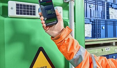 Sasch Container mit Sensoren, im Vordergrund ein hochgehaltenes Smartphone mit Barcode auf dem Bildschirm