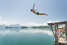 Foto zeigt einen Mann in der Luft, ins Wasser springend 