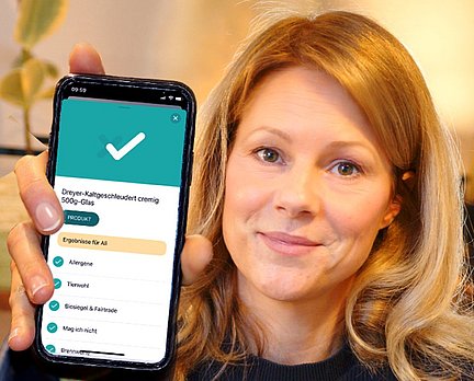 Meike Seidel hält Handy in die Kamera. Auf dem Display ist die SoVi App zu sehen.
