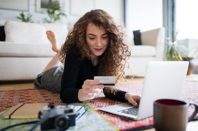 Frau vor Laptop beim Onlineshopping mit Kreditkarte in der Hand