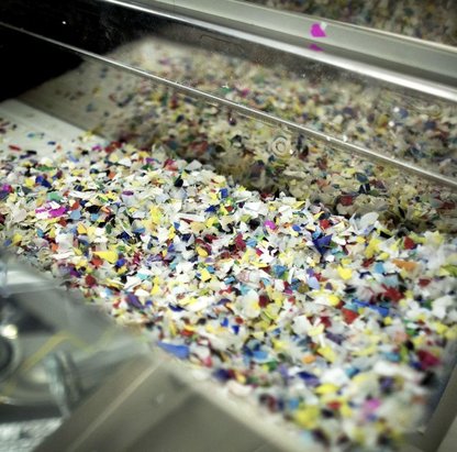Foto zeigt farbige Kunststoff Flakes, die als Rezyklat wiederverwendet werden