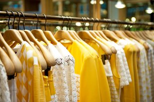 Gelbe und weiße T-Shirts auf Kleiderstange in Geschäft