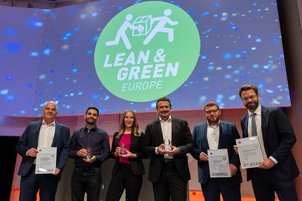 reisträger:innen der Lean and Green Auszeichnungen auf dem DLK 2023 auf der Bühne vor Lean and Green Logo