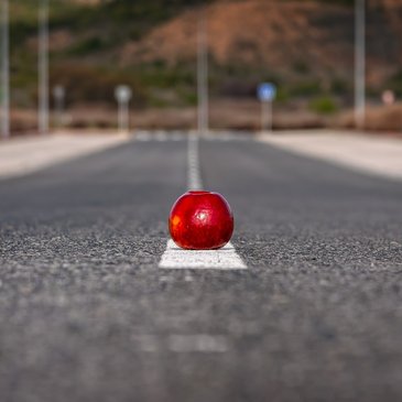 Bild: Ein roter Apfel liegt auf der Markierung mitte auf der Fahrbahn 