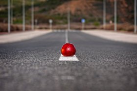 Bild: Ein roter Apfel liegt auf der Markierung mitte auf der Fahrbahn 