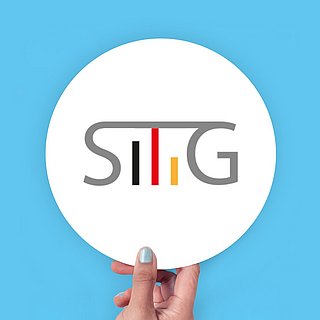 Eine Hand hält eine weiße Fläche mit dem Logo des Spitzenverband SITiG