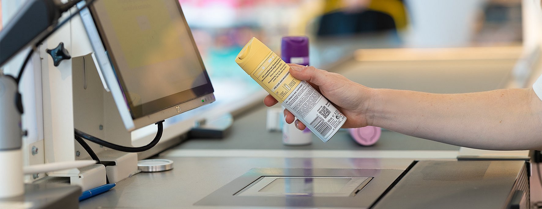 Eine Person scannt den 2D-Code an der Kasse ein