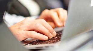 Webinar Person tippt auf einem Laptop
