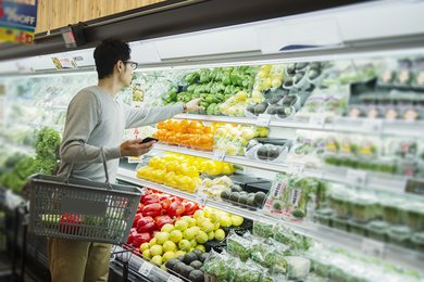 Ein Mann greift im Supermarkt in das Gemüseregal