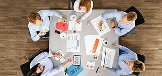 5 Personen aus dem PMO-Team sitzen planend an einem Tisch