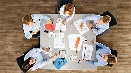 5 Personen aus dem PMO-Team sitzen planend an einem Tisch