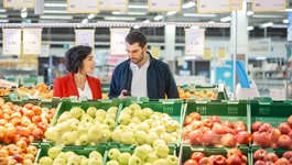 Zwei Personen unterhalten sich zwischen Supermarktregalen