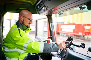 LKW-Fahrer bedient Handy in Fahrerkabine