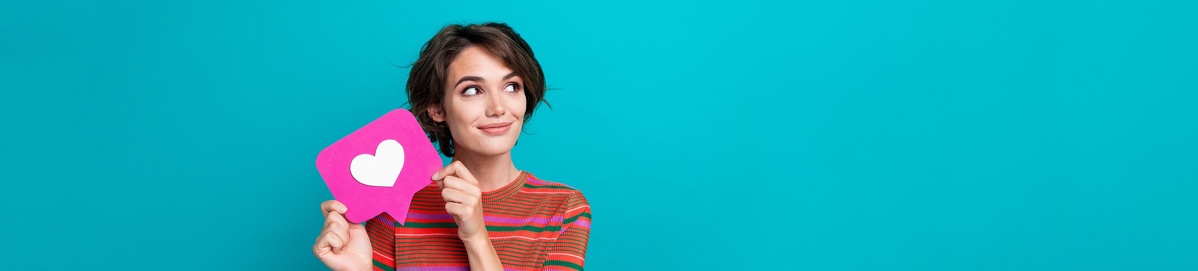 Eine junge Frau hält eine Sprechblase mit einem Herz hoch