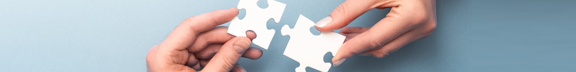 Hände fügen zwei Puzzleteile zusammen
