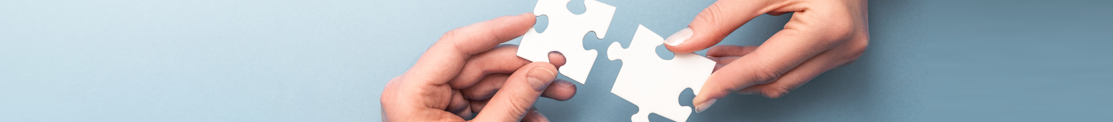 Hände fügen zwei Puzzleteile zusammen